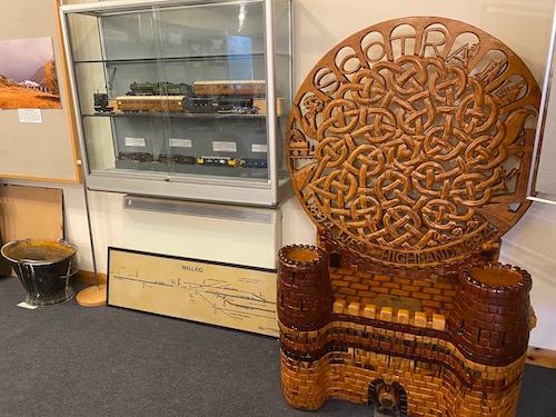 an intricately carved wooden chair and some exhibits in the background