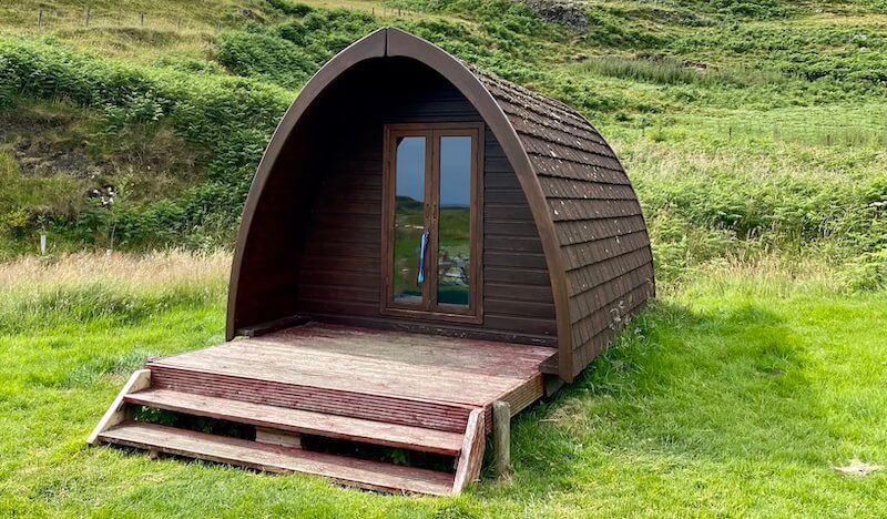 wooden camping pod surrounded by green fields
